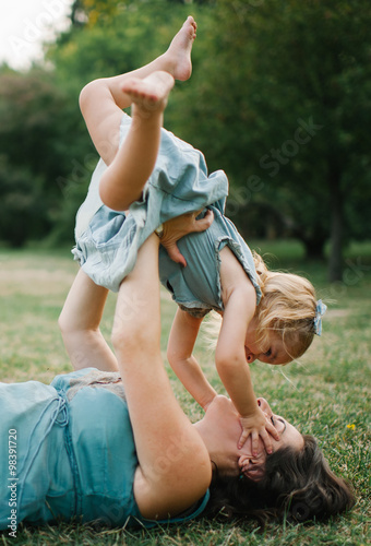 Happy young hipster family having fun while running, bowl,  rising up, piggyback ride their children in park on summer sunset
