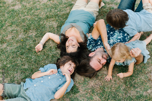 Happy young hipster family having fun while running, bowl,  rising up, piggyback ride their children in park on summer sunset
