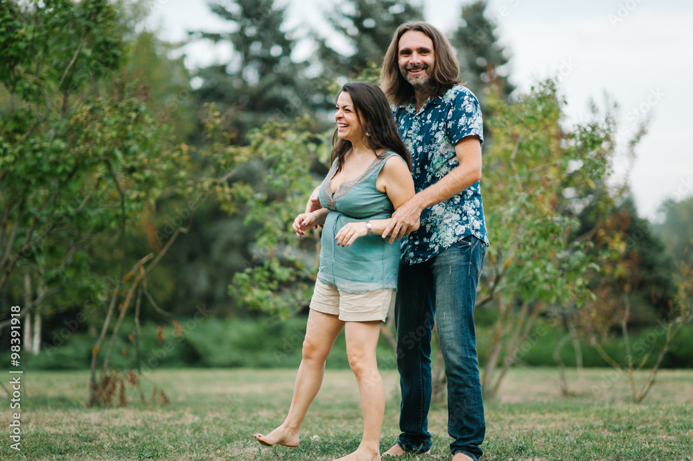 Fototapeta premium Happy young hipster family hug each other in park on summer sunset 