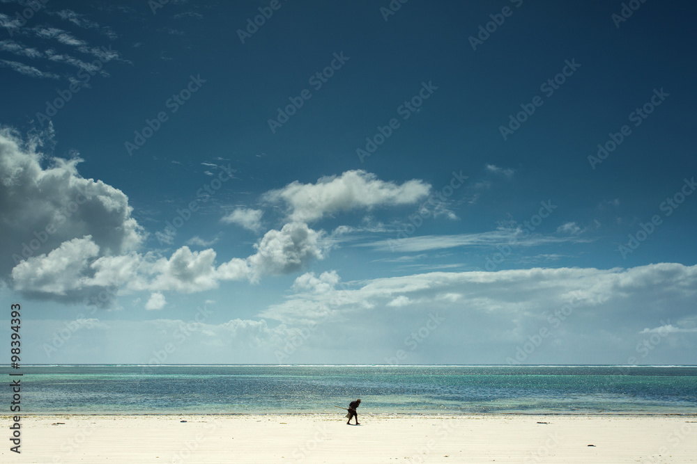 Man on a white beach in Zanzibar with blue sky