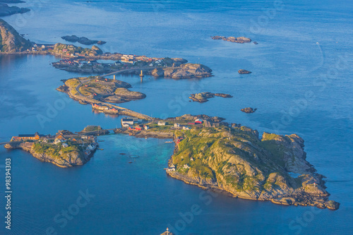 Aerial view of small seaside town situated at the foot of a mountain,bridge, green islands and sea at sunset in Norway