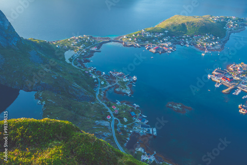 Aerial view of small seaside town situated at the foot of a mountain,bridge, green islands and sea at sunset in Norway