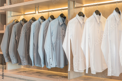 row of shirts hanging on rack with buttons