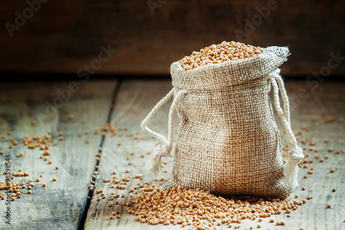 Grain mustard in a bag of sackcloth on the old wooden table, sel photo