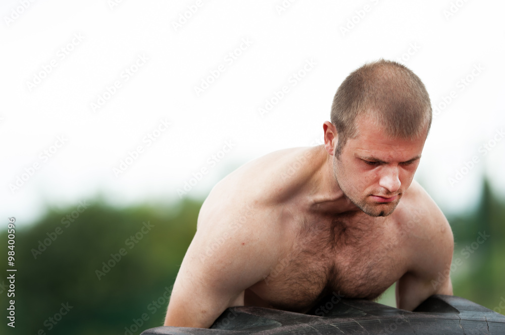 Obraz premium Young man does strongman exercise