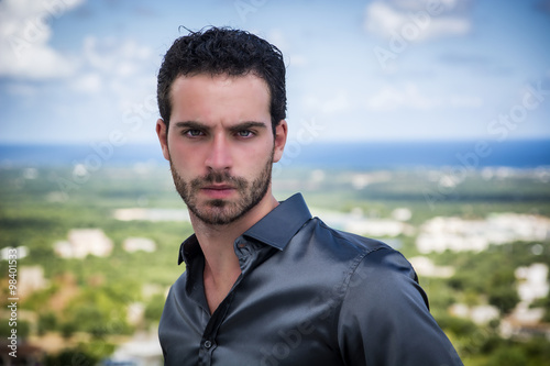 Portrait of man with curly hair standing against of shoreline