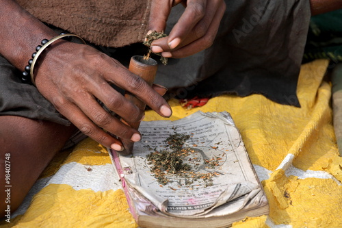 Sadhu is preparing his chillum to smoke ganja (marihuana) photo