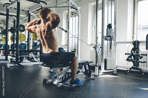 Physical athlete exercising with cable machine