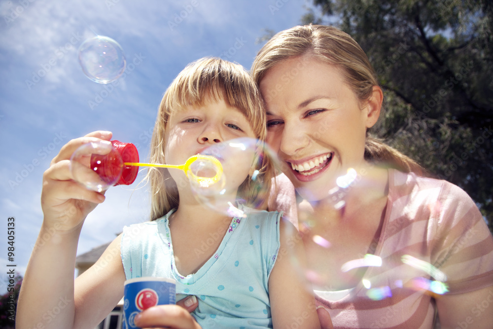 Woman and her little daughter blowing soap bubbles Woman and her little daughter blowing soap bubbles
