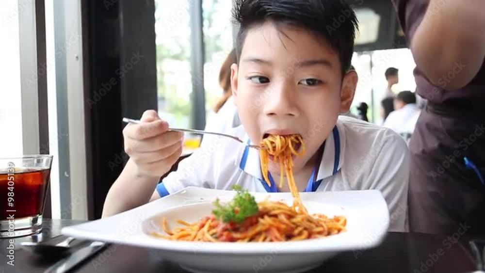 little Asian boy eating spaghetti at restaurant with smile face little Asian boy eating spaghetti at restaurant with smile face