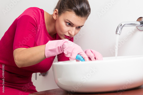 Pedantic woman cleaning washbasin photo