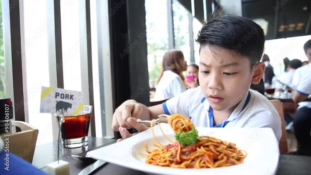 little Asian boy eating spaghetti at restaurant with smile face little Asian boy eating spaghetti at restaurant with smile face
