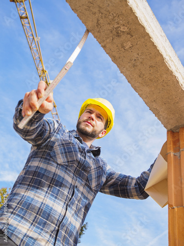 Portrait of foreman with construction plan and pocket rule checking construction work photo