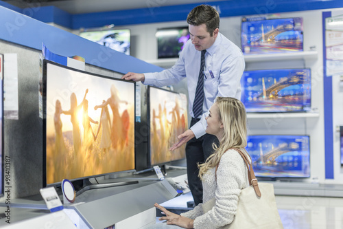 Shop assistant showing flat screen TV to customer
