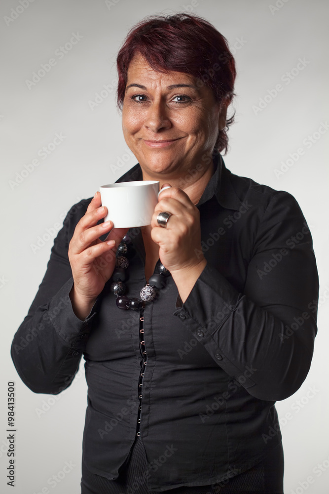 Mature woman isolated on gray background holding a coffee cup Mature woman isolated on gray background holding a coffee cup