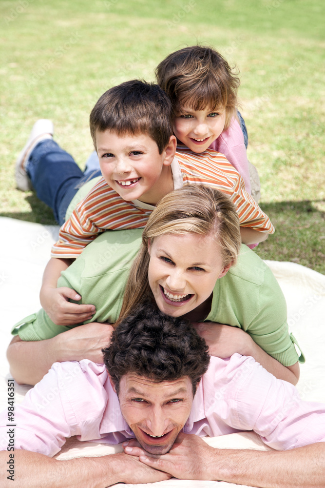 Group picture of happy family lying on top of each other on blanket in the garden Group picture of happy family lying on top of each other on blanket in the garden