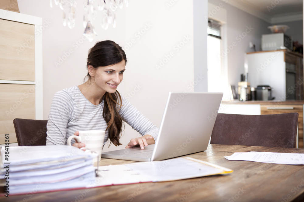 Smiling woman sitting at wooden table with cup of coffee and laptop Smiling woman sitting at wooden table with cup of coffee and laptop