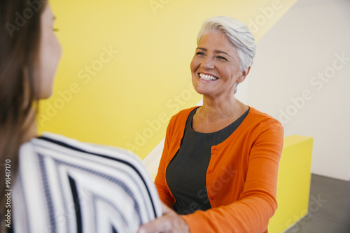 Portrait of smiling mature woman greeting another woman in an office