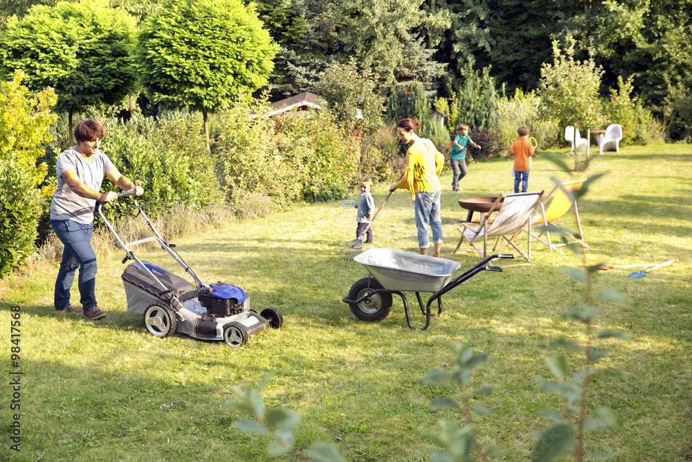 Father mowing the lawn in garden Father mowing the lawn in garden
