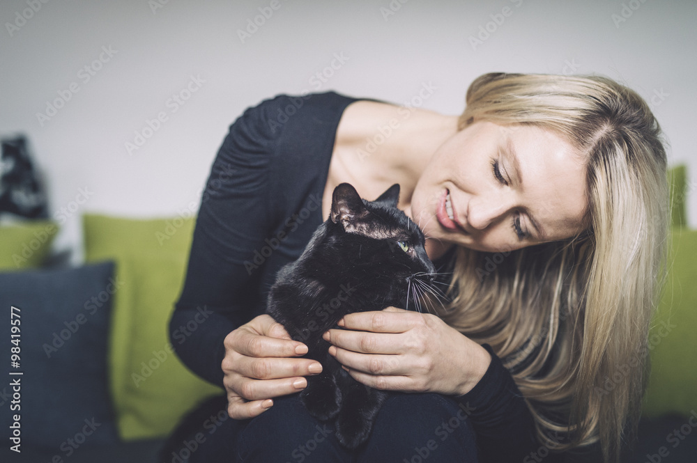 Blond woman and her black cat on the couch Blond woman and her black cat on the couch