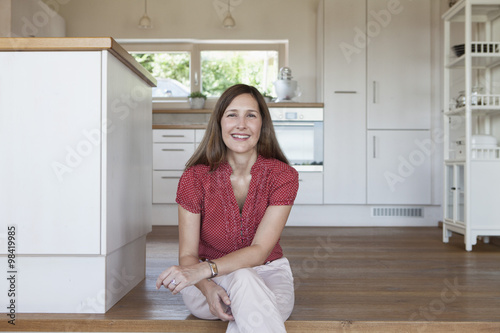 Mature woman sitting on kitchen steps, looking confident photo