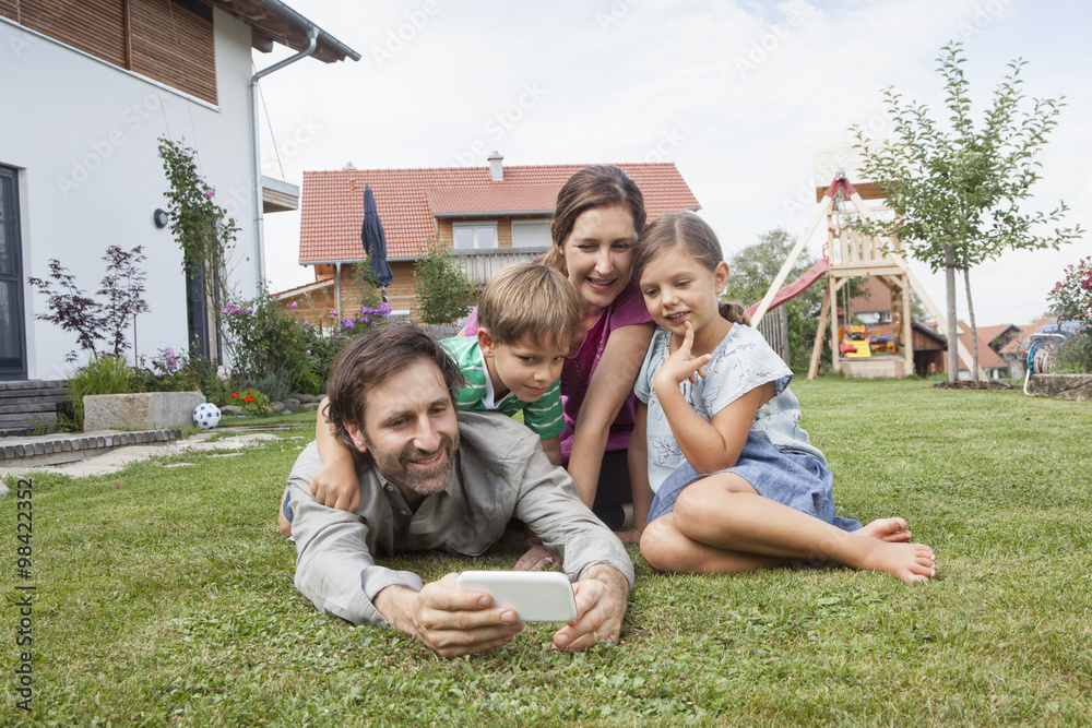 Smiling family of four in garden with cell phone Smiling family of four in garden with cell phone