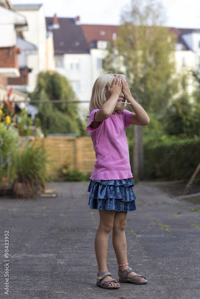 Little blond girl playing hide and seek Little blond girl playing hide and seek