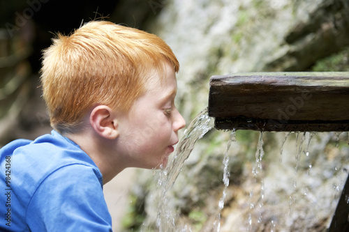 Boy drinking water from a runlet