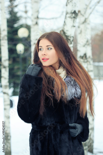 beautiful smiling girl on background of snowy trees. Winter portrait. coat with a hood photo