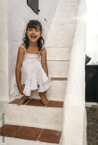 Spain, Balearic Islands, Menorca, Binibeca, portrait of laughing little girl sitting on a step