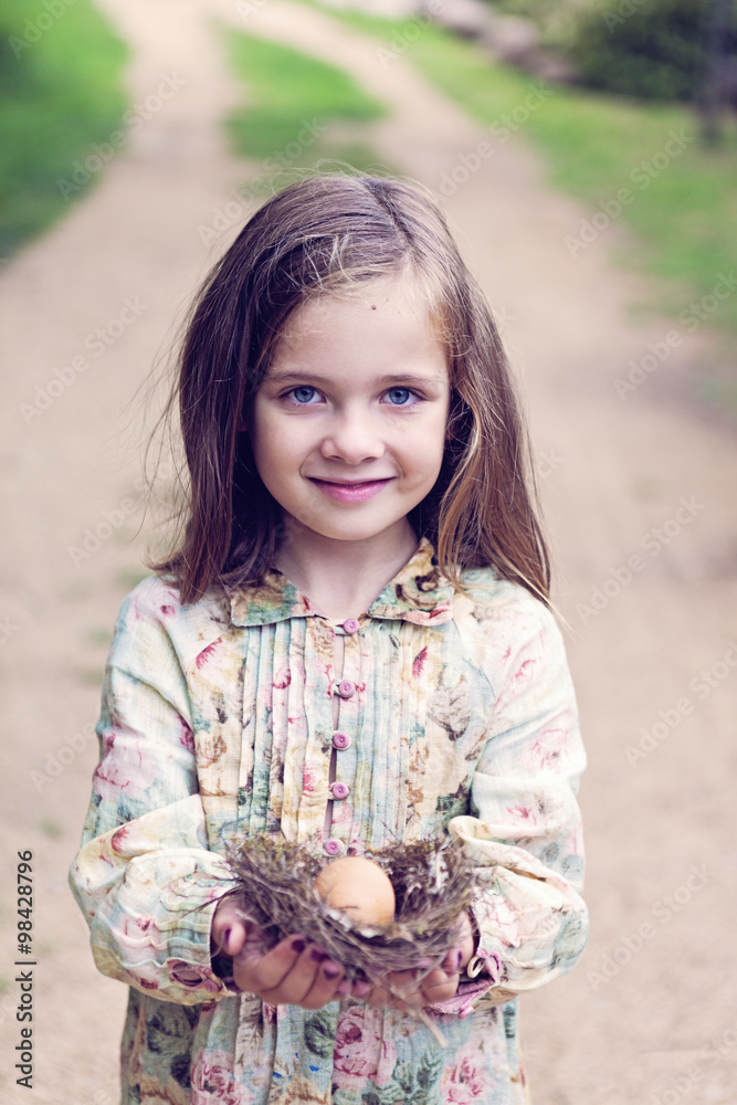 Smiling girl holding an egg in a nest