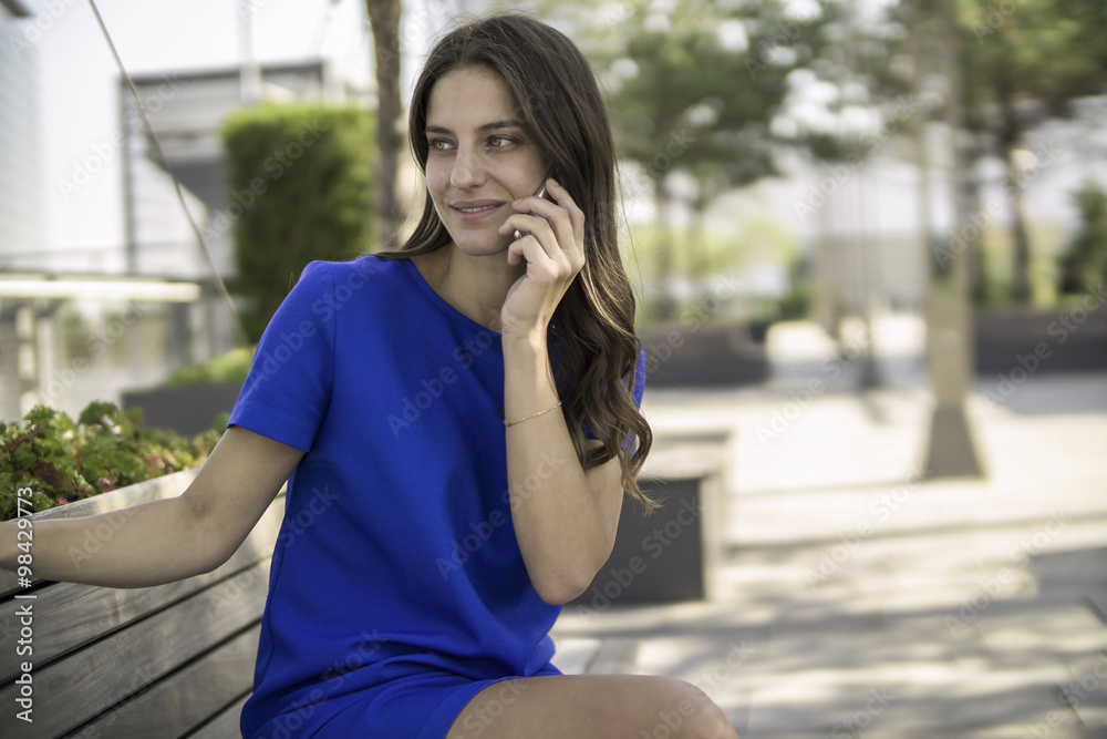 Smiling businesswoman sitting on a bench telephoning with smartphone Smiling businesswoman sitting on a bench telephoning with smartphone