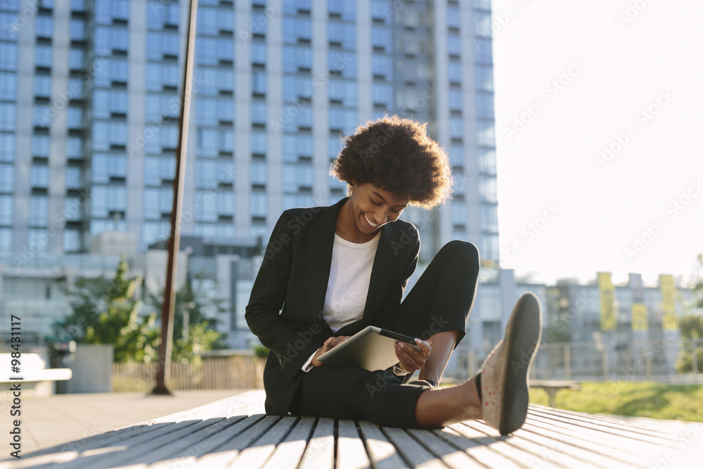 USA, New York City, businesswoman sitting on a bench using digital tablet USA, New York City, businesswoman sitting on a bench using digital tablet