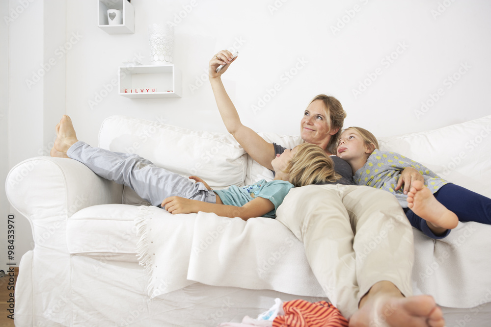 Mother, daughter and son on couch taking a selfie Mother, daughter and son on couch taking a selfie