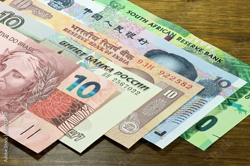 Banknoten der BRICS Staaten auf Holzhintergrund photo