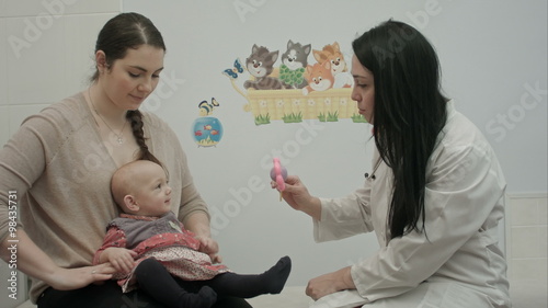 Cute baby being examine by pediatrician with toy