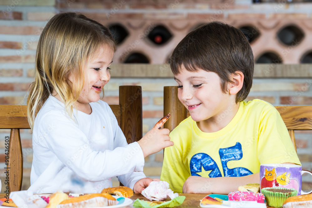 Fototapeta premium Pareja de niños jugando en la mesa con restos de comida