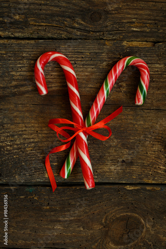 Closeup of two old fashioned candy canes on a rustic wooden back