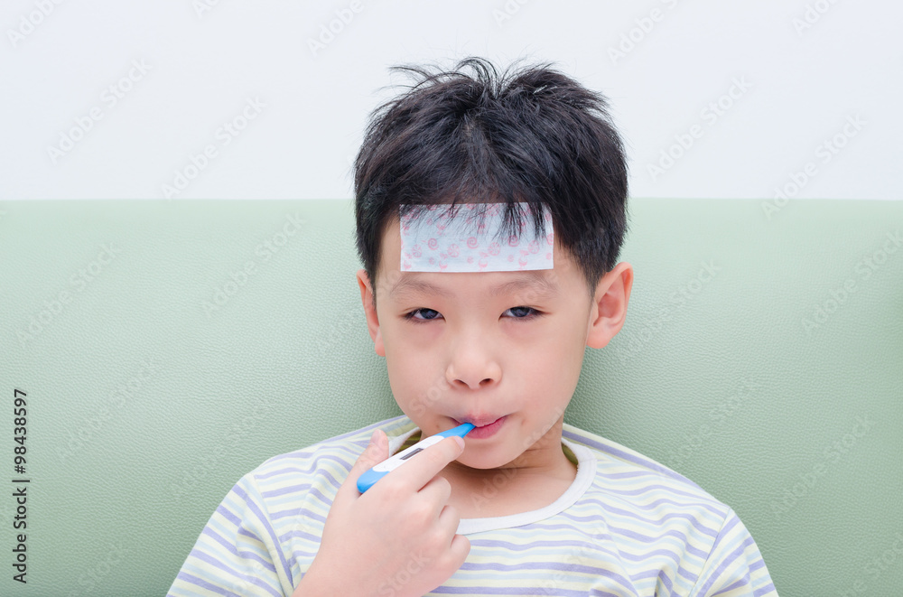 Little sick boy sitting on sofa with thermometer in mouth Little sick boy sitting on sofa with thermometer in mouth