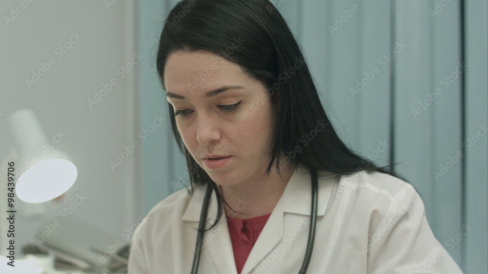 Female doctor in medical office analyzes results an electrocardiogram and takes notes Female doctor in medical office analyzes results an electrocardiogram and takes notes