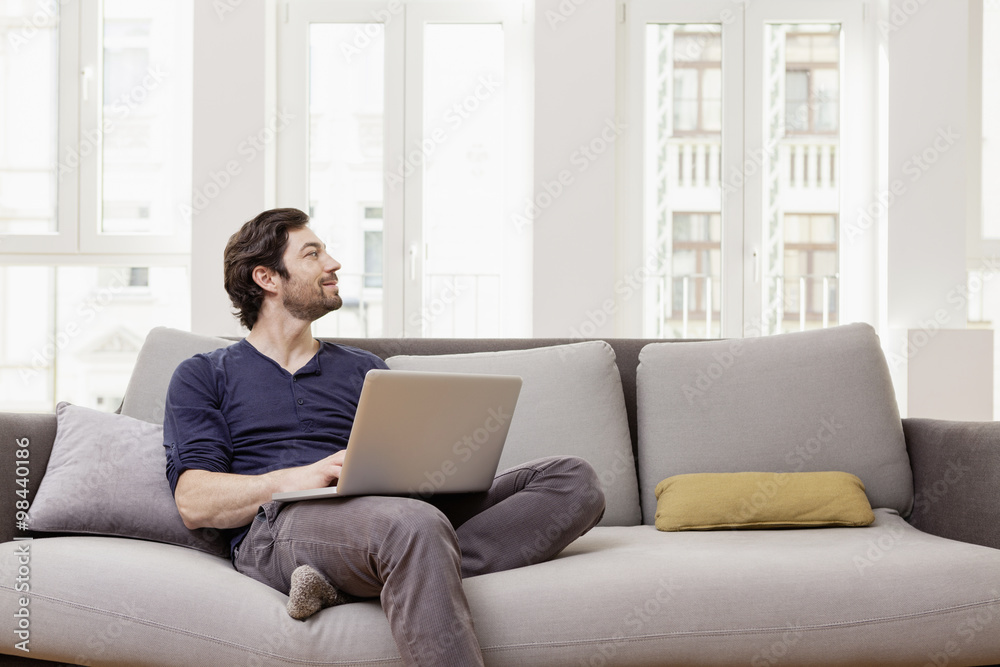 Man sitting on couch using laptop Man sitting on couch using laptop