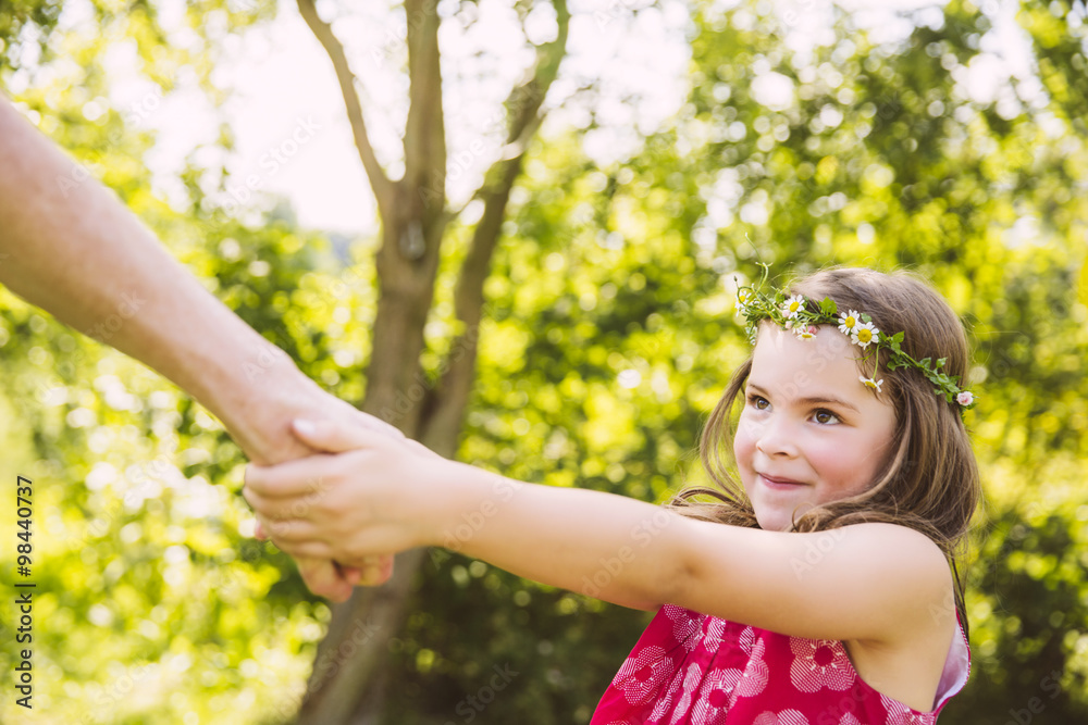 Girl pulling adult's arm in garden Girl pulling adult's arm in garden