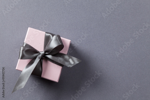Pink box with gray ribbon and bow on a gray background