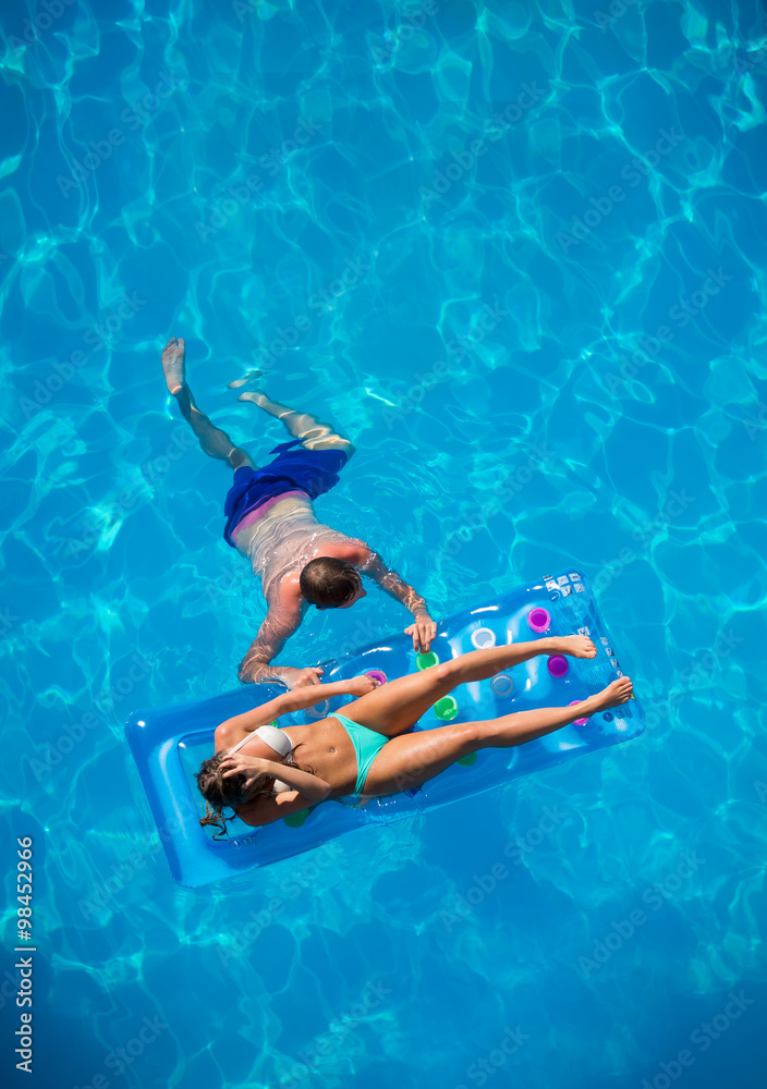 Couple relaxing on a lilo mattress at the swimming pool