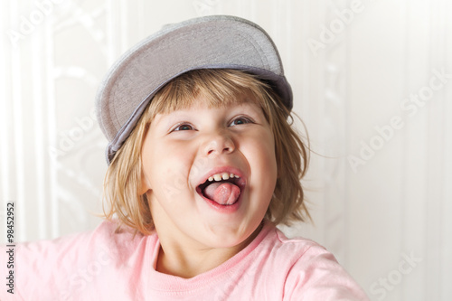 Funny laughing cute Caucasian blond baby girl in cap