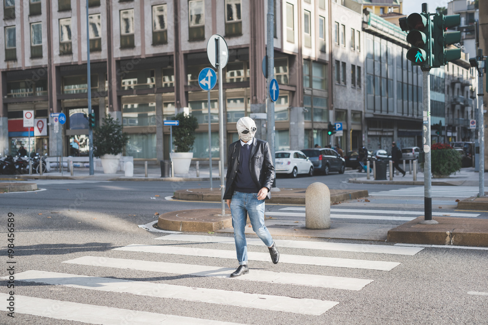 Young handsome caucasian man walking through pedestrian crossing, wearing an alien mask - surreal, eccentri concept Young handsome caucasian man walking through pedestrian crossing, wearing an alien mask - surreal, eccentri concept