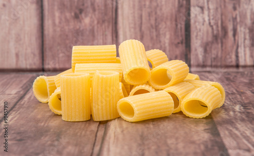 Rigatoni pasta or tube shaped pasta over wooden background photo