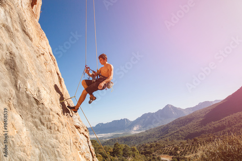 Male rock climber on belay rope