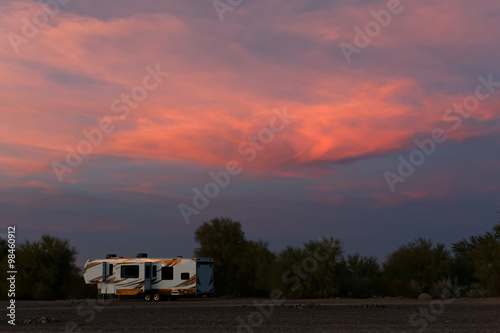 large rv alone against sunset clouds