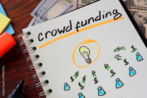 Notebook with crowd funding  sign on a table. Start up concept. photo